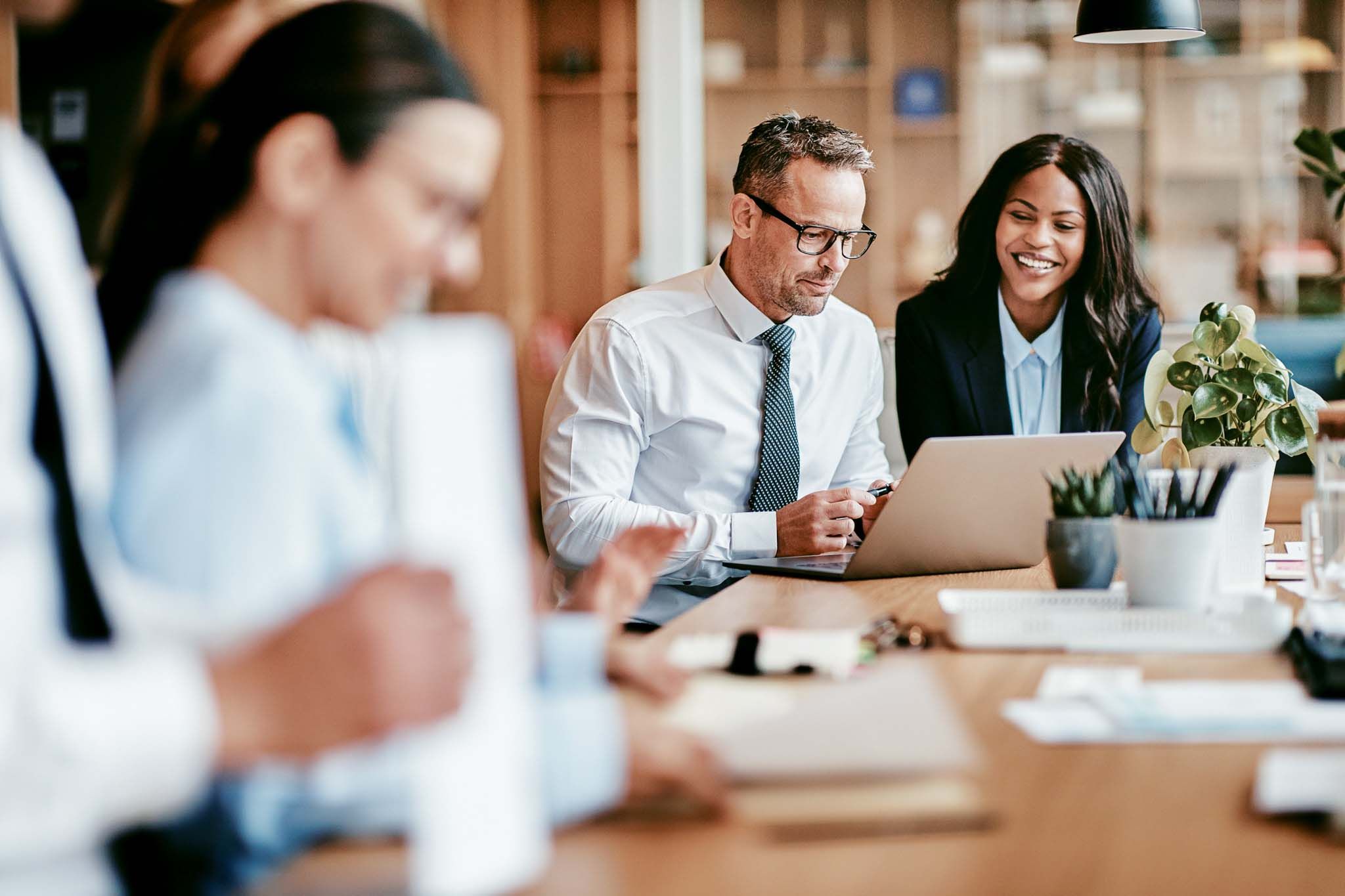 Two smiling diverse businesspeople using a laptop together at work