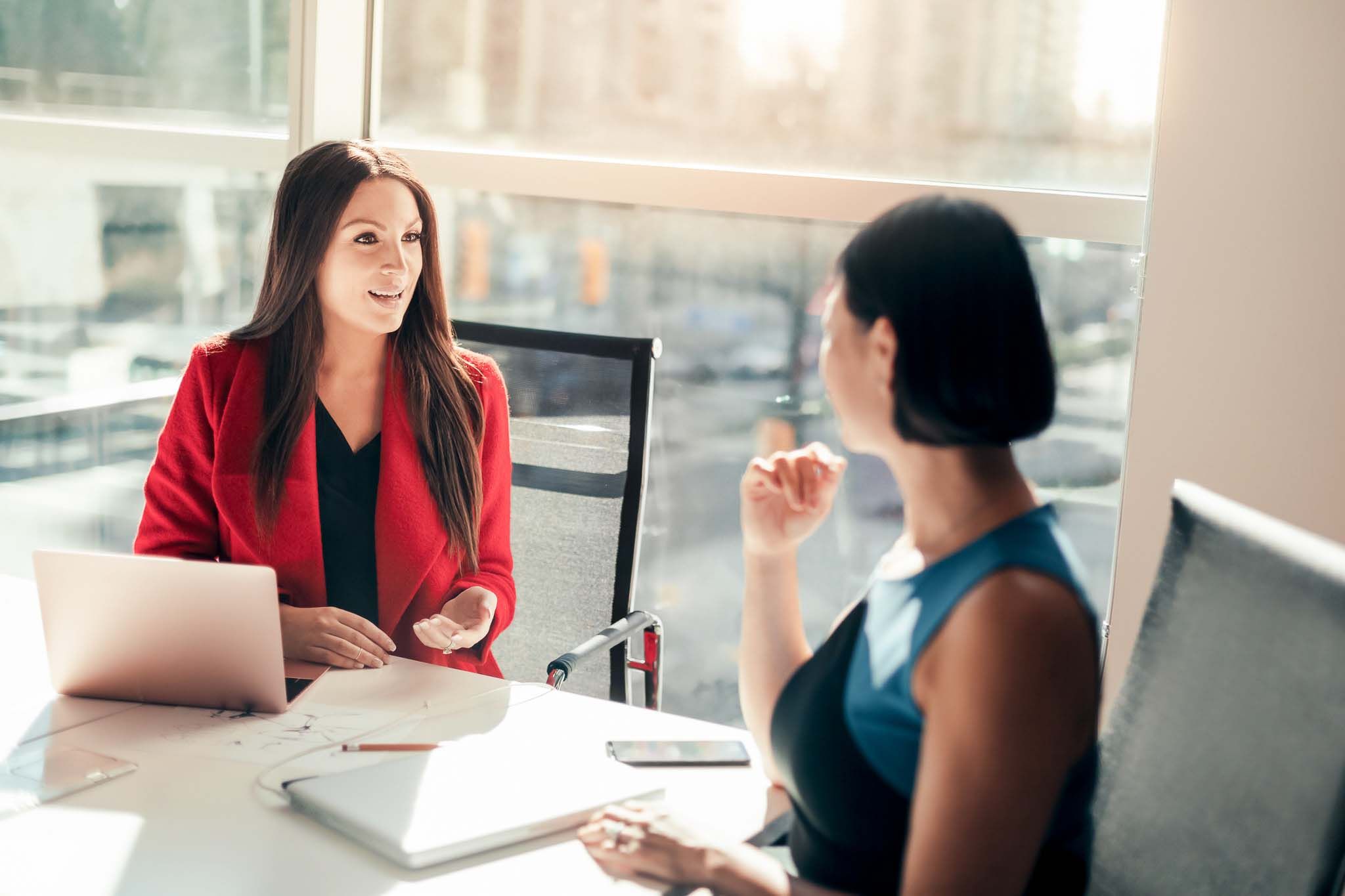 Two business women colleagues discussing project together in modern office