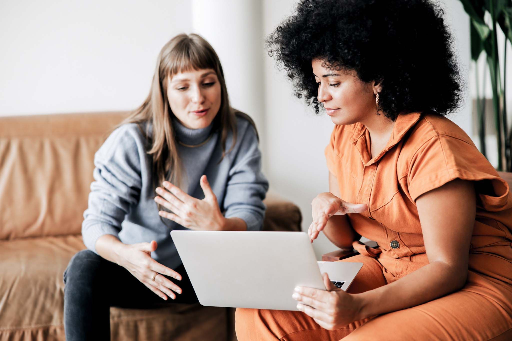 Two businesswomen having a discussion while looking at a laptop screen