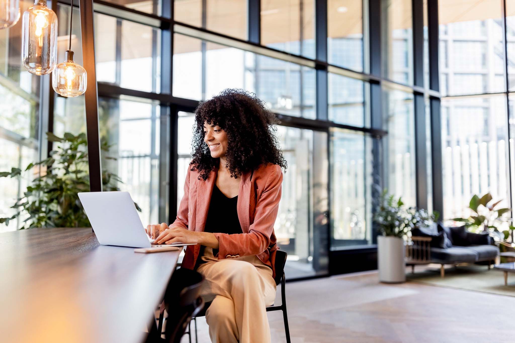 Young African woman working on laptop at office cafe